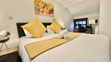 A hotel room with a large bed, a desk, a chair, and a painting on the wall.