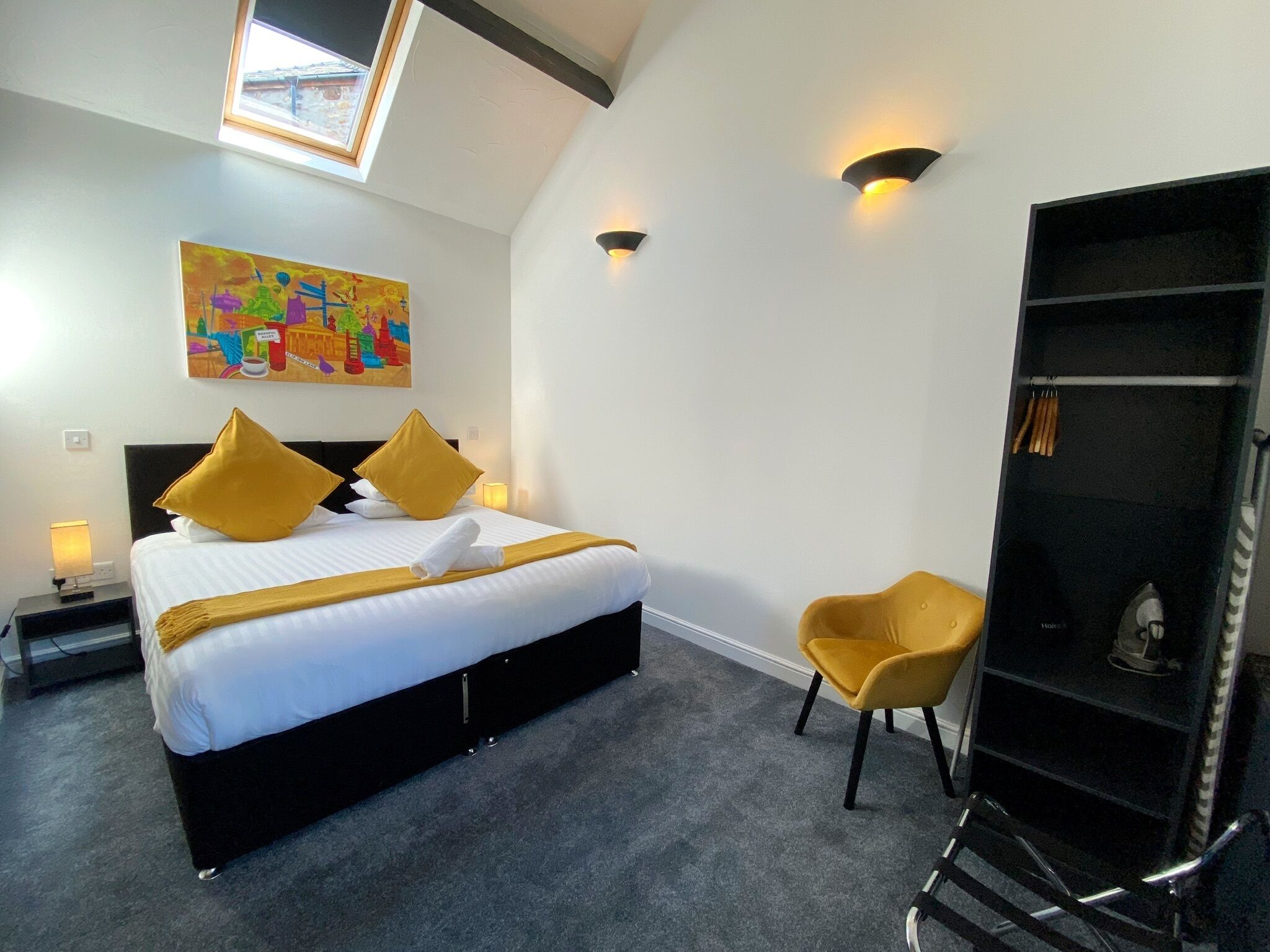 Habitación de hotel con cama, una silla, armario y un cuadro en la pared.