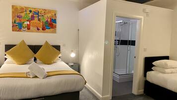 A hotel room with a bed, a nightstand, a bedside lamp, a shower, and a colorful painting on the wall.