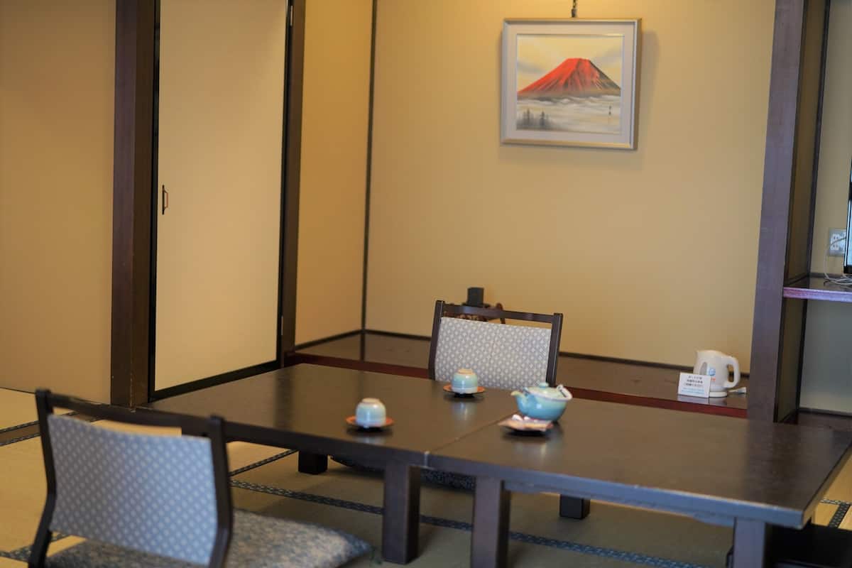 Una mesa de comedor con sillas, un cuadro en la pared y una tetera sobre la mesa.