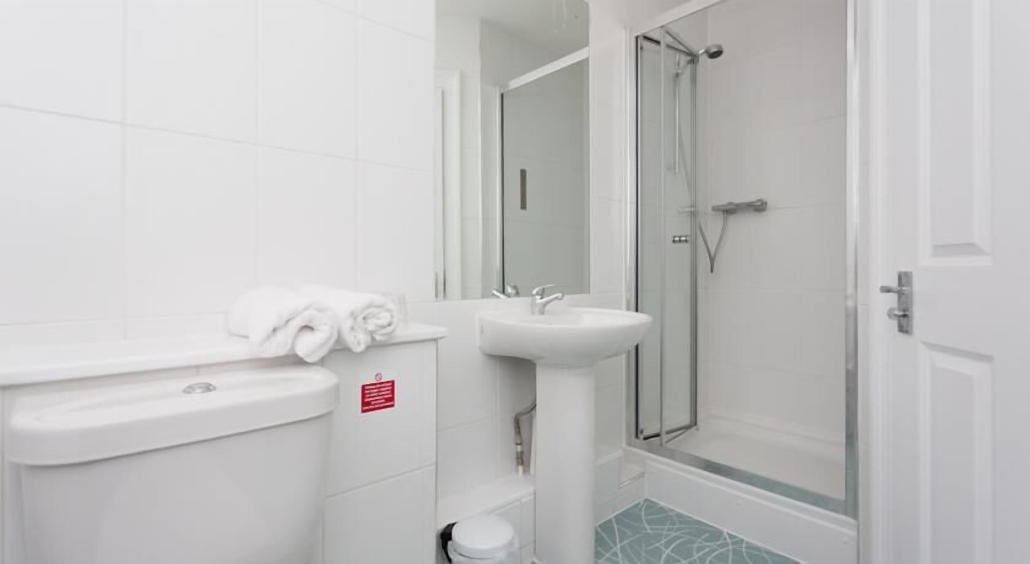 Un bagno moderno con WC, lavandino e cabina doccia in vetro.