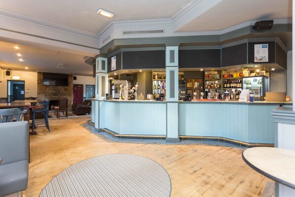 A bar area with a counter, seating, and a stone fireplace.
