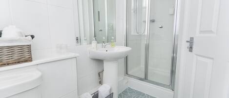 A modern bathroom with a glass-enclosed shower, a white sink, and a tiled floor.