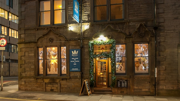 A historic building with a sign for the Royal Hotel & Bar, featuring a traditional facade and illuminated windows. - The Royal Hotel and Bar (Lancaster)