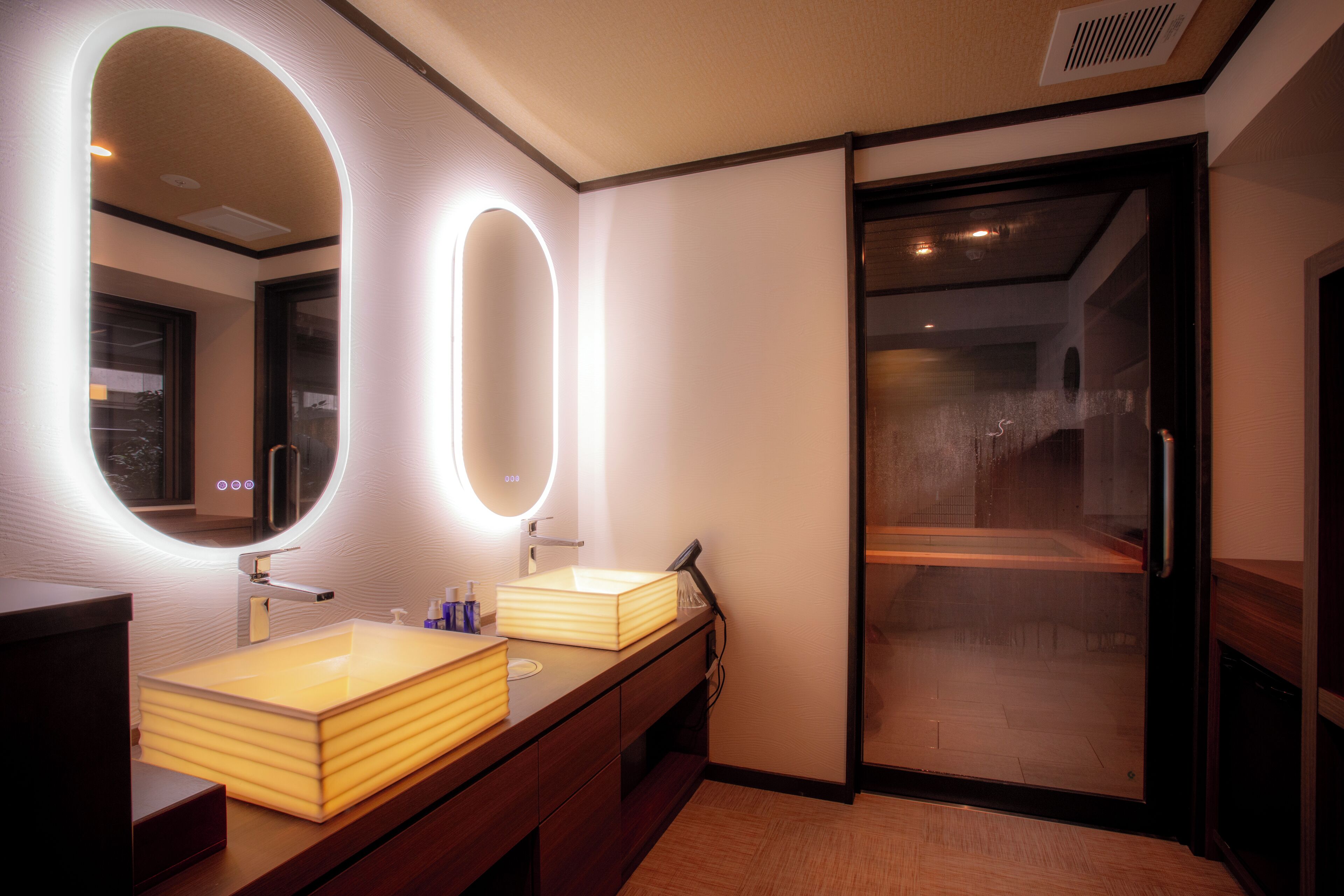 A modern bathroom with two sinks, a large mirror, and a shower area.