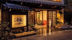 Un edificio japonés tradicional con techo de tejas, un sendero de piedra y un letrero con caracteres japoneses.