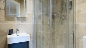 A modern bathroom with a glass-enclosed shower, a white sink, and a toilet.