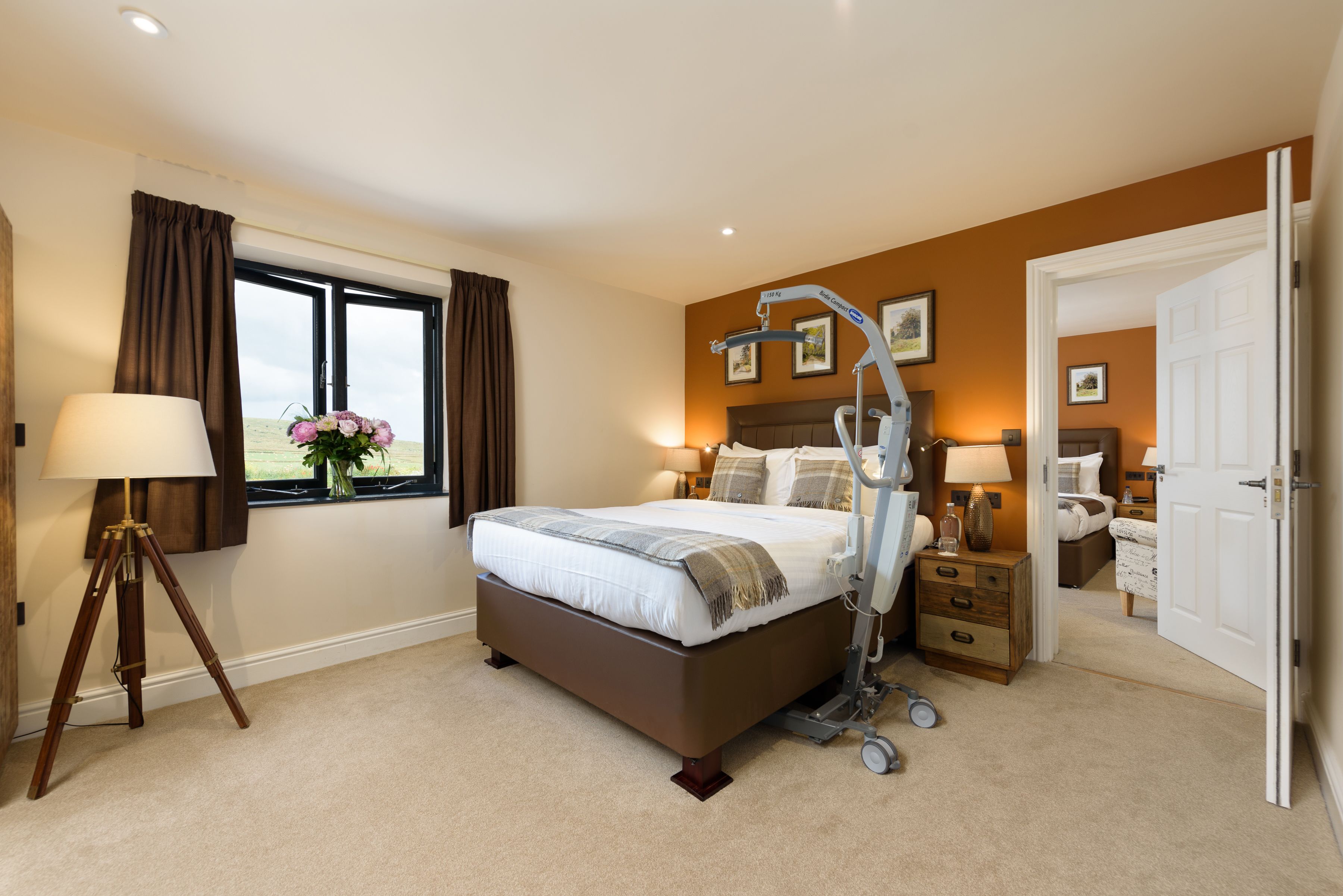 A bedroom with a large bed, bedside tables, a lamp, a window with curtains, and a view of the outdoors.