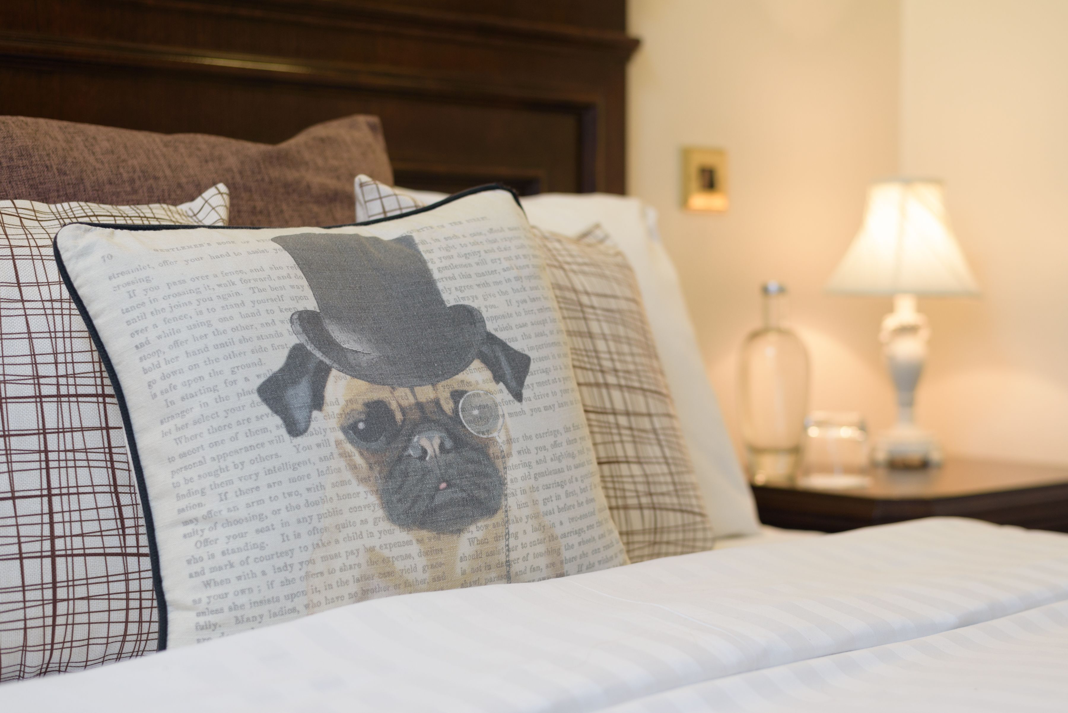 A bed with a pillow featuring a dog illustration, a bedside lamp, and a nightstand.