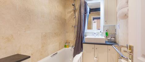 A modern bathroom with a bathtub, a shower, and a sink.