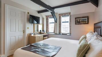 A hotel room with a large bed, a dresser, a television, and a window with curtains.