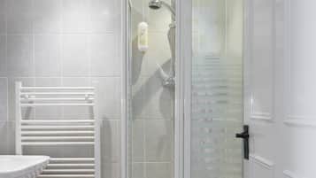 Un baño moderno con ducha de vidrio, una bañera blanca y un lavamanos blanco.