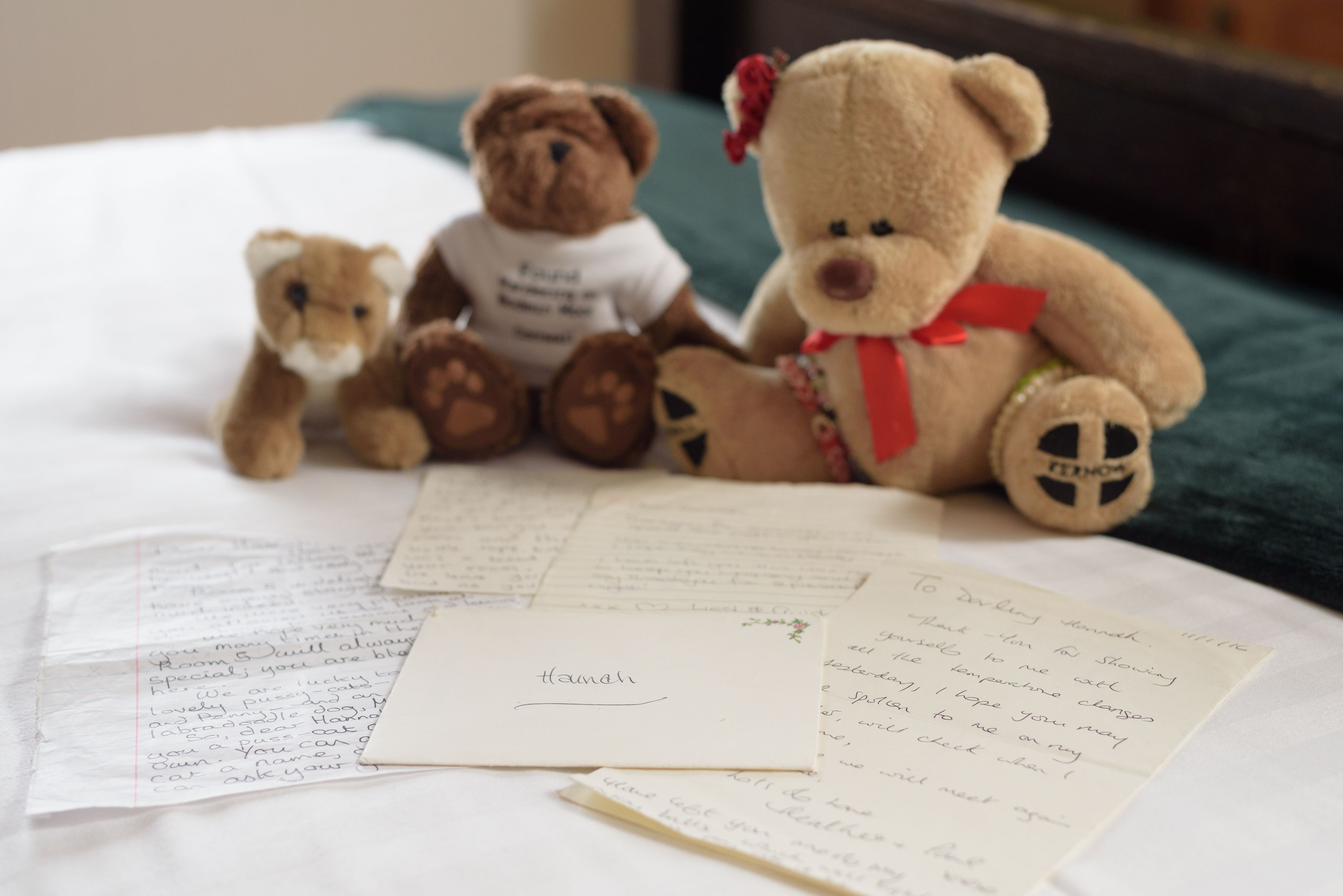 Ein Bett mit drei Teddybären und handgeschriebenen Notizen.