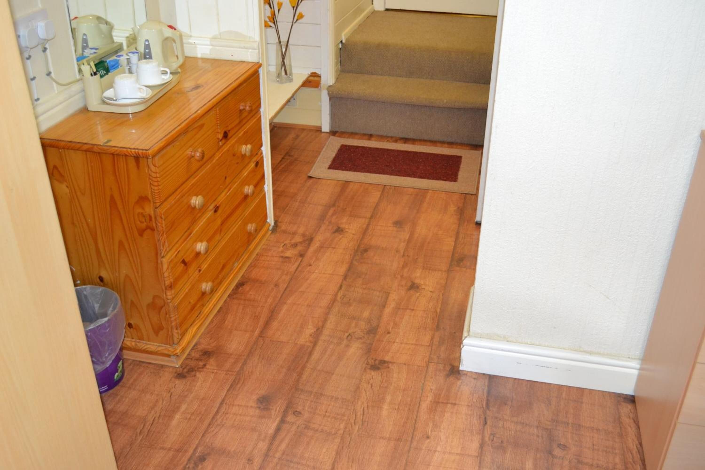 A wooden dresser with drawers, a small rug, and a staircase leading to a landing.