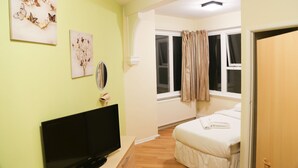 Ein Schlafzimmer mit einem Bett, einem Fernseher und Kunstwerken an der Wand.