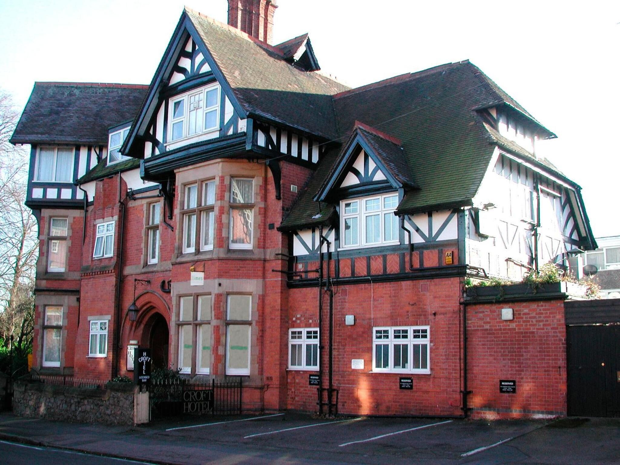 A traditional building with a prominent entrance, multiple windows, and a sign indicating it is a hotel.