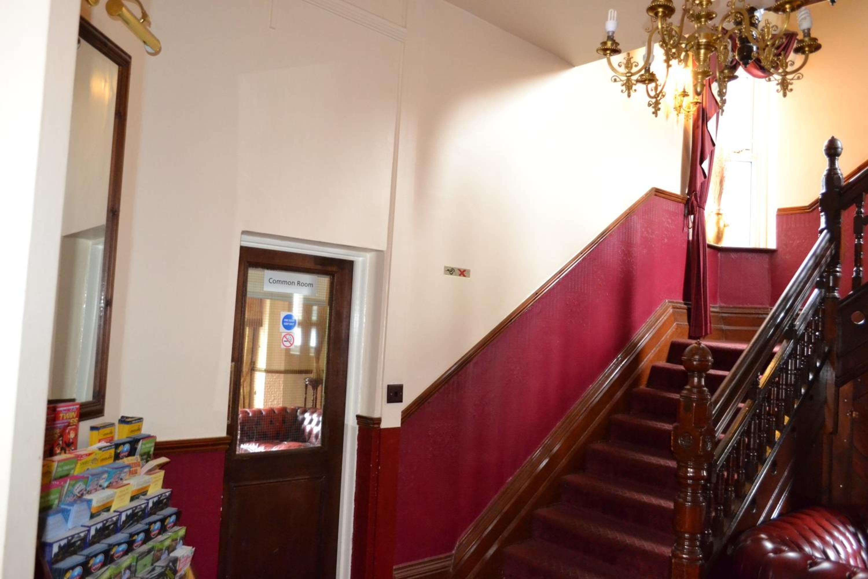 A staircase with a wooden handrail and a chandelier.