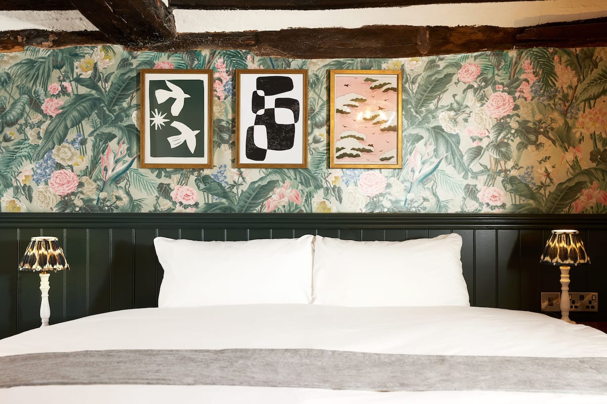 A bed with white linens, a dark headboard, and two bedside lamps.