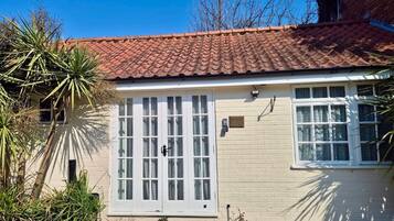 A single-story house with a tiled roof, a front door with glass panels, and a small porch area.