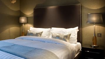 Habitación de hotel con una cama grande, dos mesitas de noche y un ventanal con cortinas.