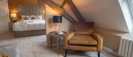 A bedroom with a bed, a chair, a table with a lamp, and a radiator.