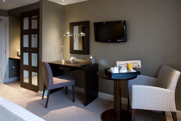 A modern hotel room with a desk, chair, and a TV mounted on the wall.