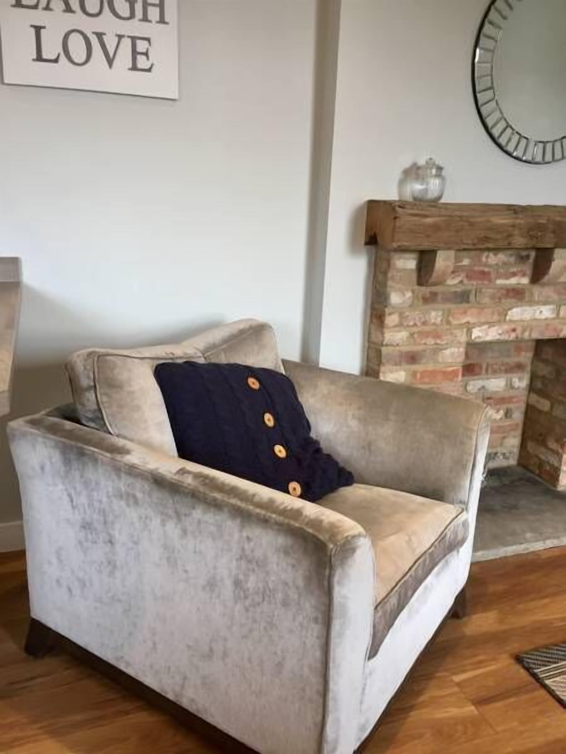 Una sala de estar con un sofá de estilo vintage, una chimenea y un cartel en la pared que dice 'LAUGH LOVE'.