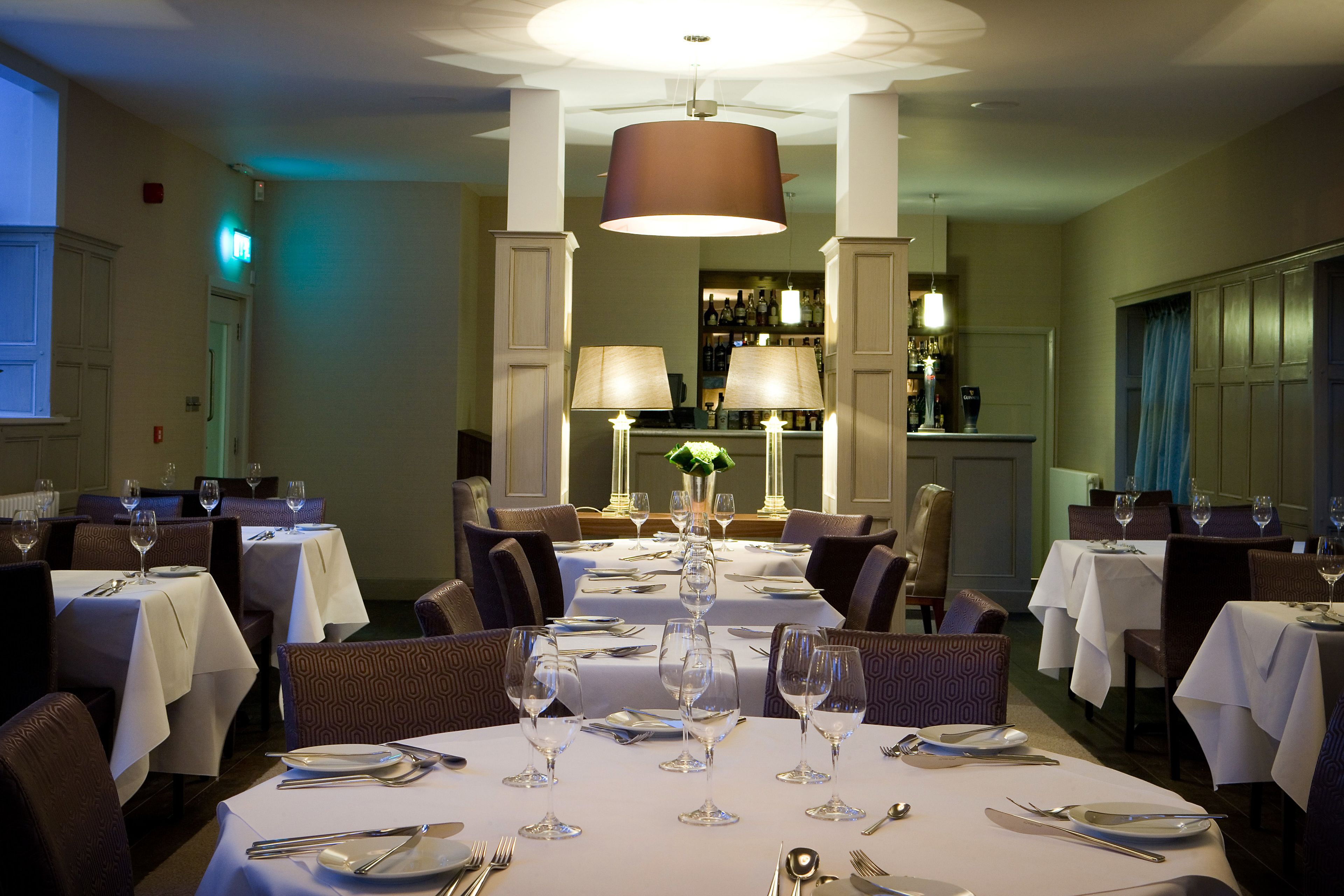 Una sala ristorante con tavoli rotondi apparecchiati, con tovaglie bianche e posateria.