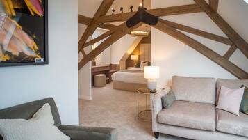 A cozy loft bedroom with exposed wooden beams, a bed, a nightstand, and a lamp.