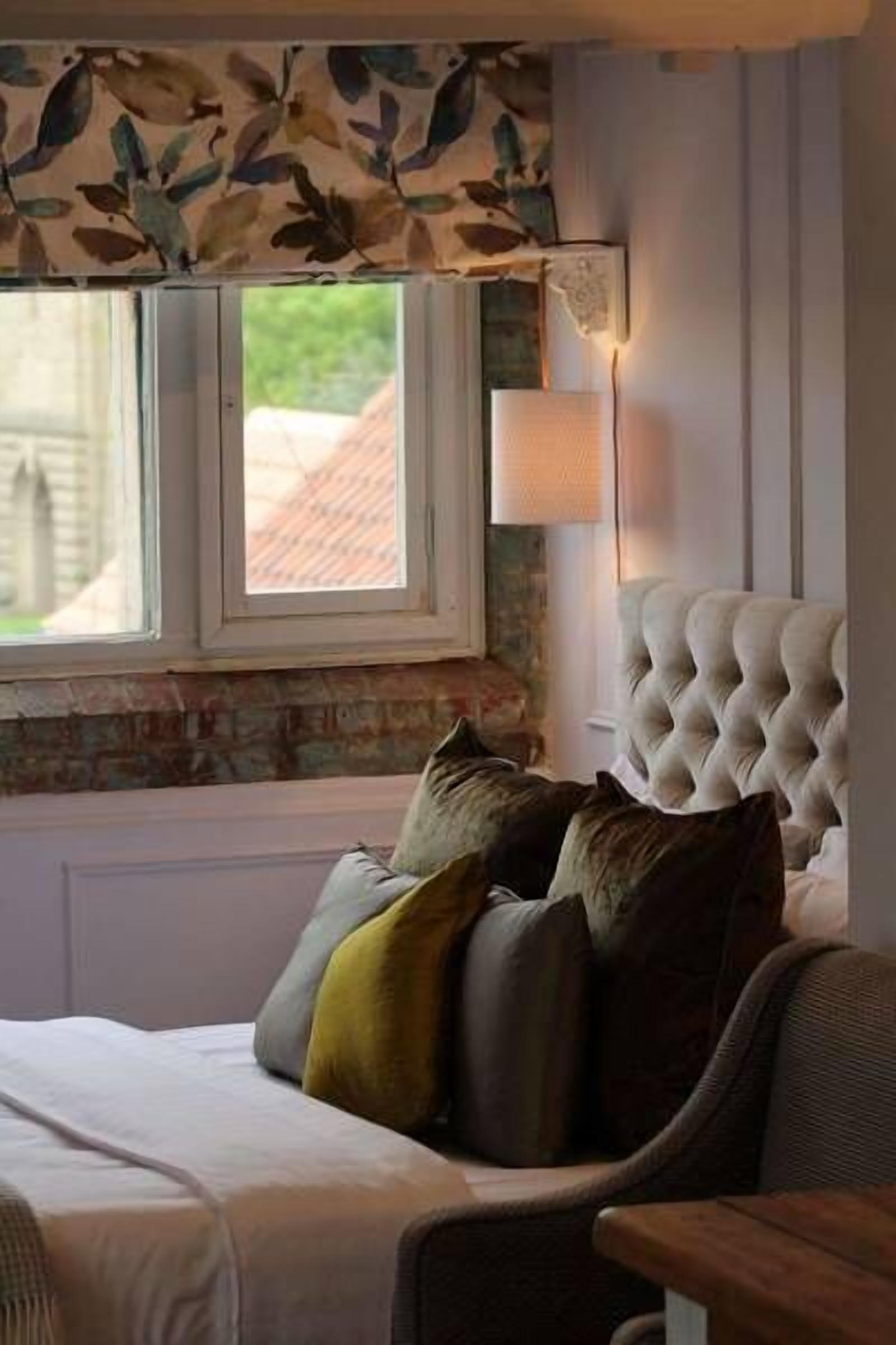 Une chambre à coucher avec un lit, une chaise, une fenêtre donnant sur un beau paysage et une lampe.