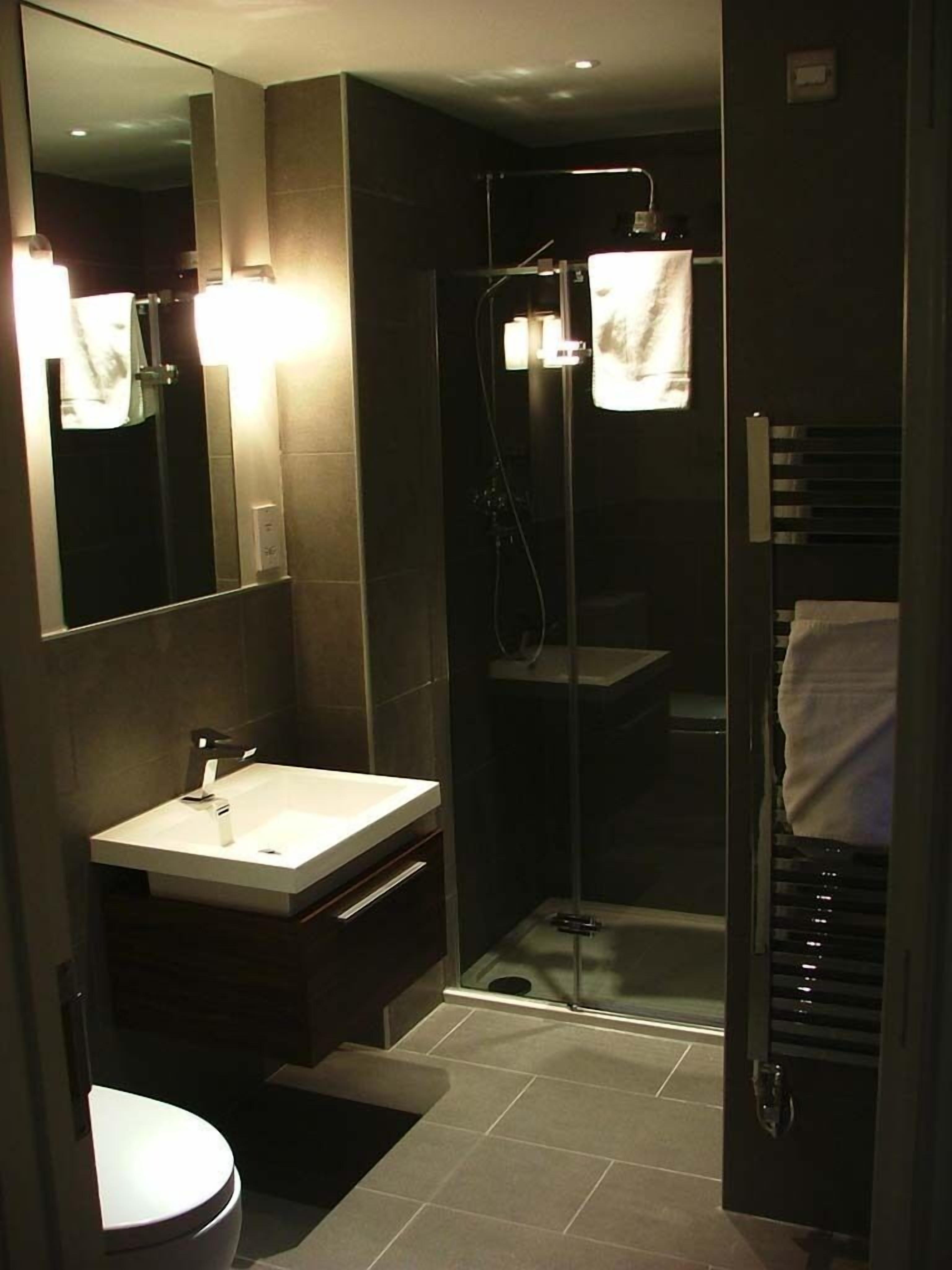 A modern bathroom with a vanity, a toilet, and a glass-enclosed shower.