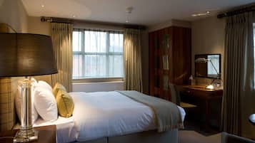 A hotel room with a bed, a desk, a lamp, and curtains.