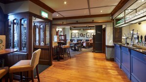A bar area with wooden flooring, bar stools, and a counter with various bottles and glasses. - Childwall Abbey, by Marstons Inns  (Liverpool)
