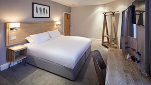 A hotel room with a large bed, wooden headboard, bedside tables with lamps, a wooden desk, and a shower area. - Childwall Abbey, by Marstons Inns  (Liverpool)