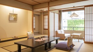 Une pièce de style japonais traditionnel, avec un sol recouvert de tatamis, une table basse, un canapé et des portes coulissantes.