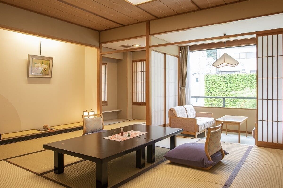 Een traditionele Japanse kamer met tatami vloerbedekking, een lage tafel, een bank en schuifdeuren.