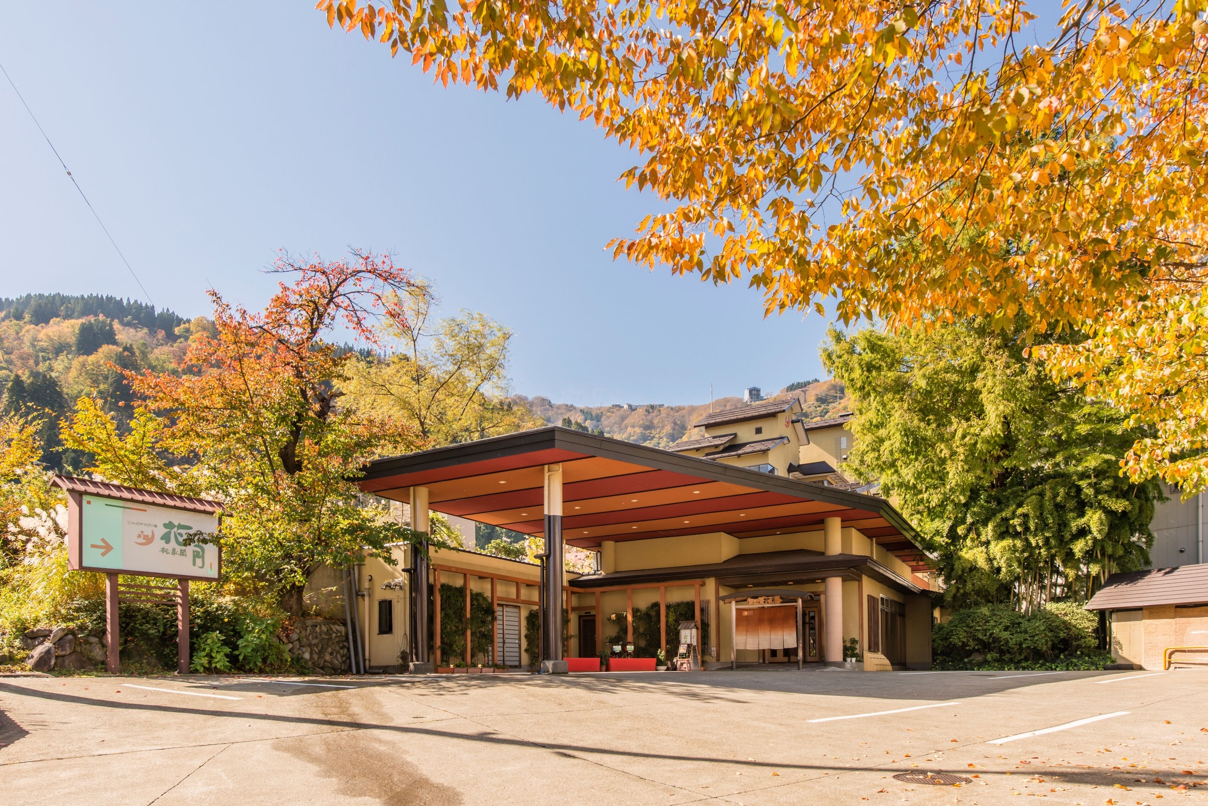 A hotel with a covered outdoor area, a sign indicating a restaurant, and a view of a hilly landscape.