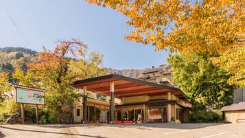A hotel with a covered outdoor area, a sign indicating a restaurant, and a view of a hilly landscape.
