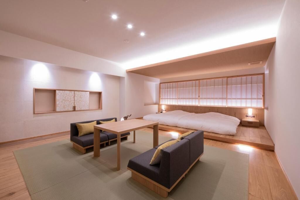 A modern, minimalist room with a low ceiling, a sofa, a table, and a bed.