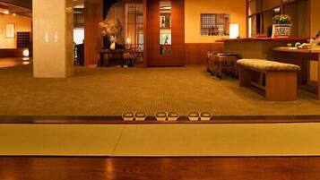 A hotel lobby with a reception desk, seating area, and a decorative vase.