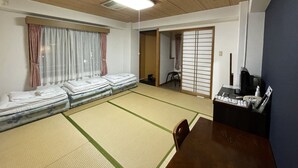 A traditional Japanese room with tatami flooring, a futon bed, a shoji screen door, and a desk with a computer and stationery. - Crystal Hiroshima (Hiroshima)