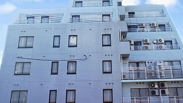 A multi-story hotel with a prominent blue and white sign at the top, multiple balconies, and a grid-like facade. - Crystal Hiroshima (Hiroshima)