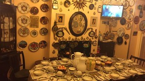 A dining room with a round table set for a meal, surrounded by various decorative plates and a fireplace. - Albany Hotel (London)