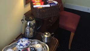 A hotel room with a complimentary mini bar, a coffee station, a red armchair, and a mirror on the wall. - Albany Hotel (London)