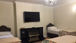 A hotel room with two beds, a flat-screen TV, a fireplace, and a chandelier. - Albany Hotel (London)