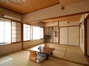 A traditional Japanese room with tatami flooring, a low table, and sliding doors. - Yorimoto Ryokan (Hiroshima)
