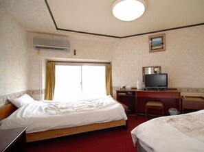 A hotel room with two beds, a desk with a television, and an air conditioning unit. - Yorimoto Ryokan (Hiroshima)