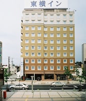 A multi-story hotel with a beige and white facade, multiple windows, and a visible entrance.