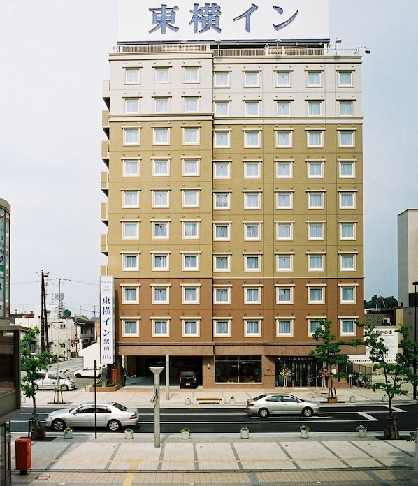 A multi-story hotel with a beige and white facade, multiple windows, and a visible entrance.
