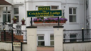 Une enseigne d’hôtel pour le Cricklewood Lodge, avec un numéro de téléphone à contacter.